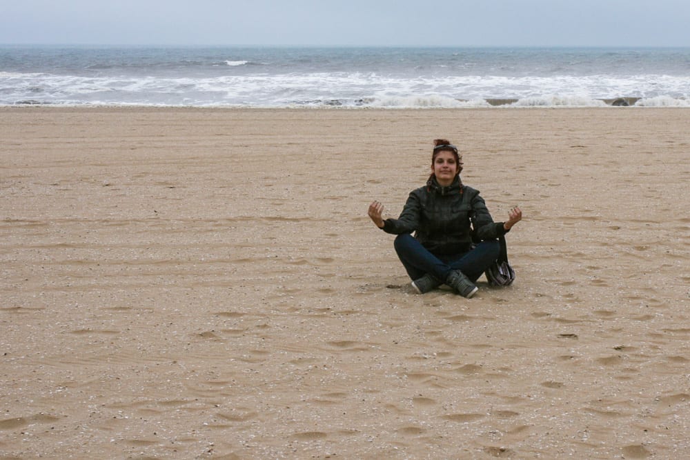 A girl meditating on a sandy beach in the Hague, The Netherlands