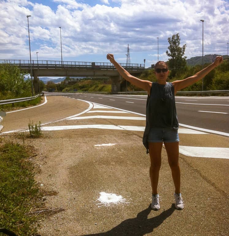 A happy hitchhiker girl in the middle of nowhere