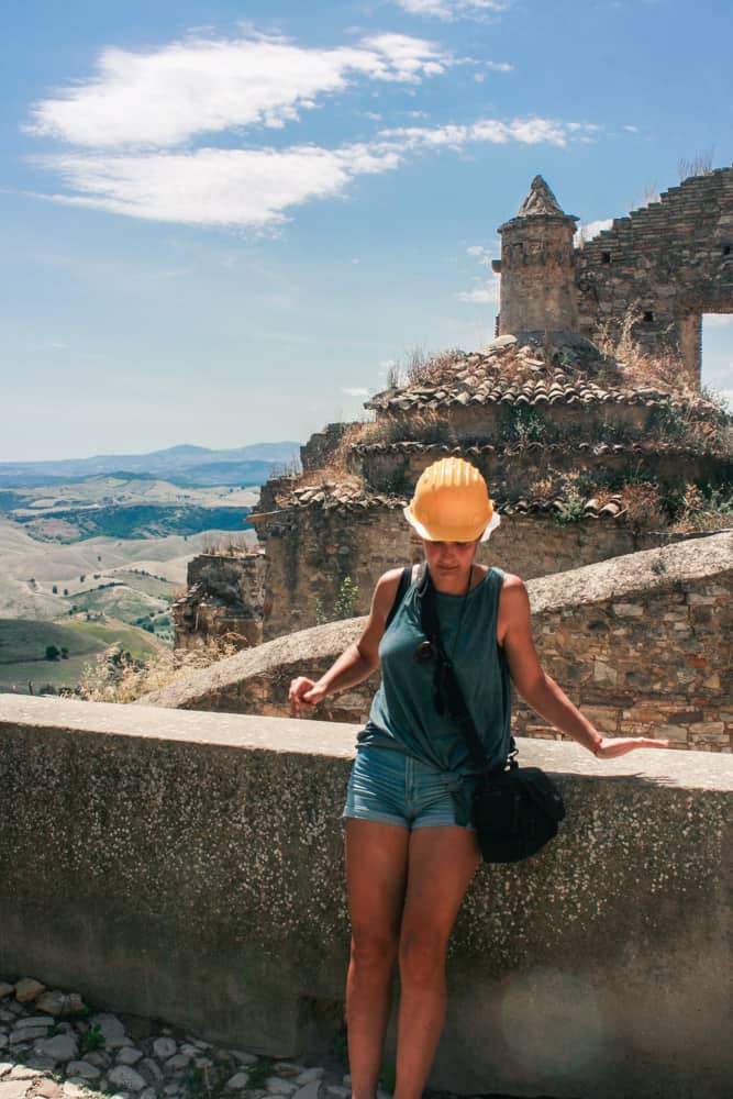 A girl with a protection hat exploring the ruins of the ghost town of Craco in Basilicata in the south end of Italy