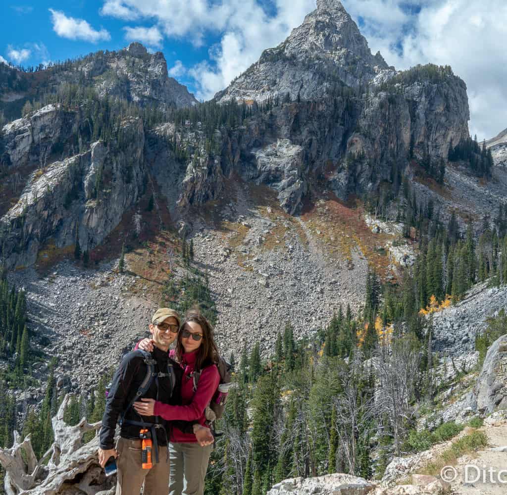 A hiking couple's photo in front of high-peaked mountain, the Grand Tetons