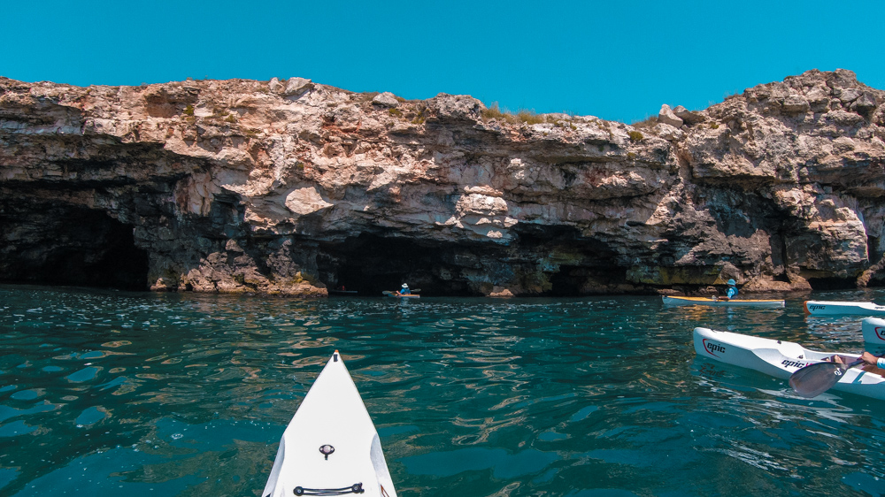 Several kayaks going into a water cave in a cliff in Bulgaria