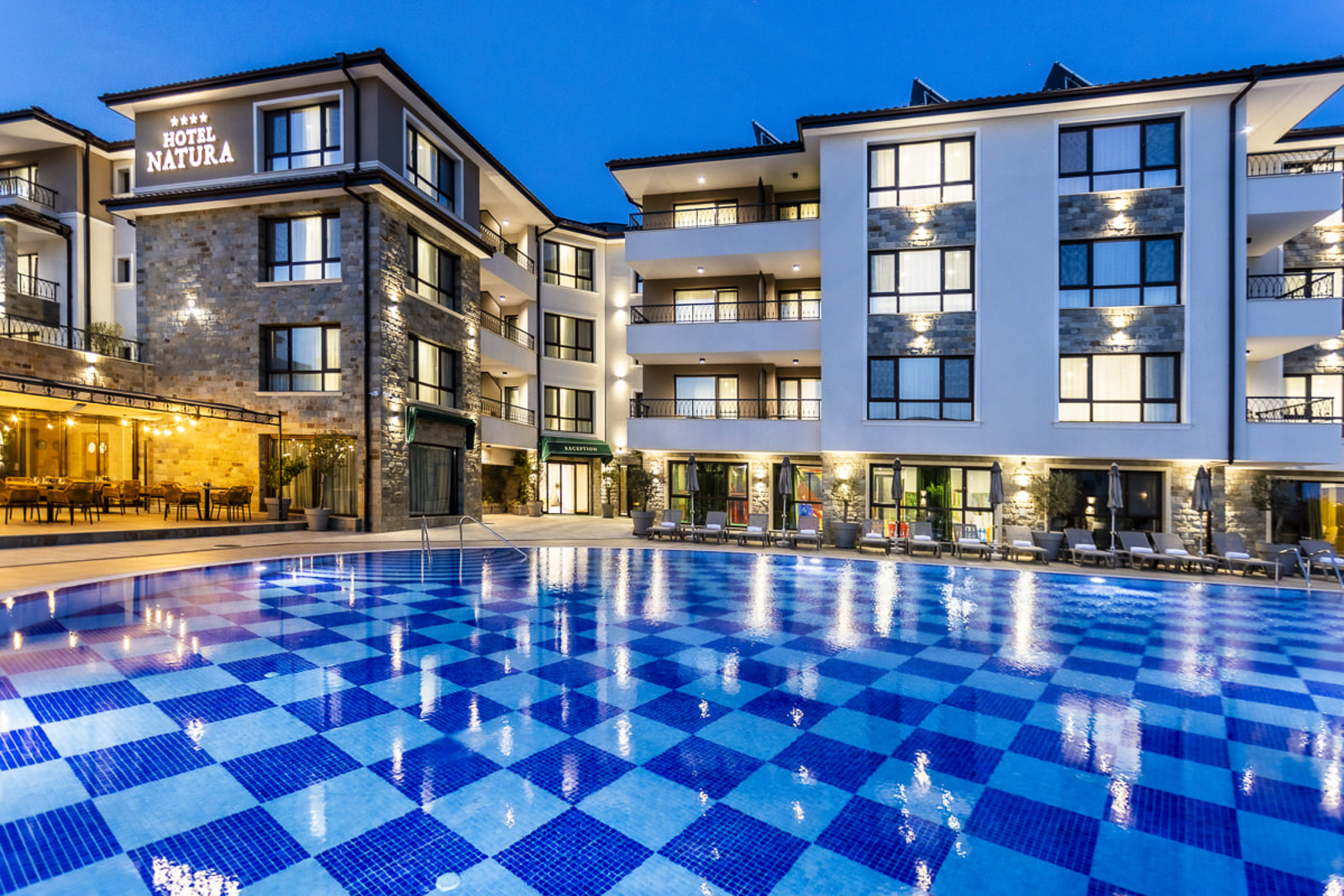 Outdoor pool with a view towards hotel Natura All Seasons in the evening with a link to affiliate booking page
