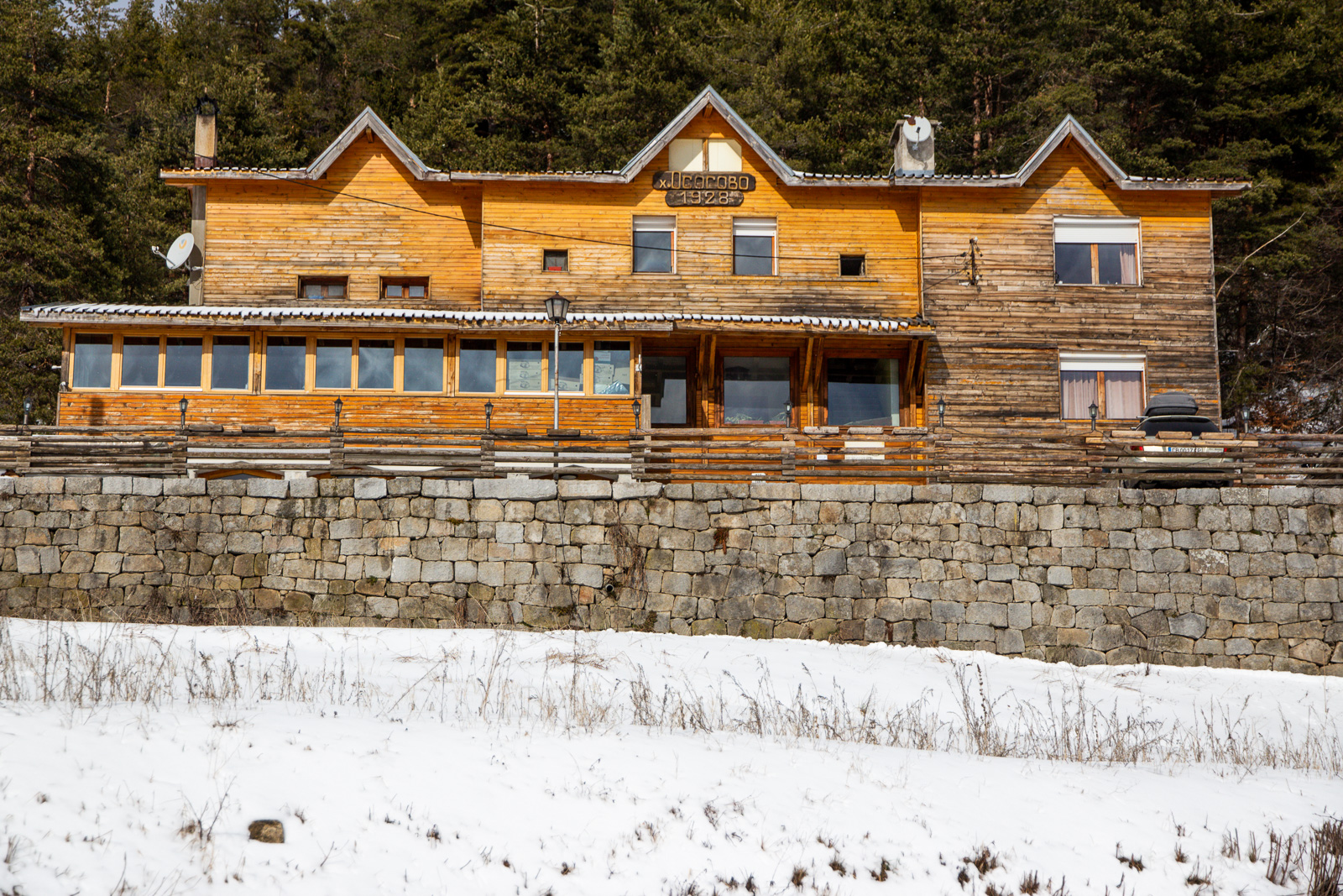 Wooden hut Osogovo with snow outside and a forest behind