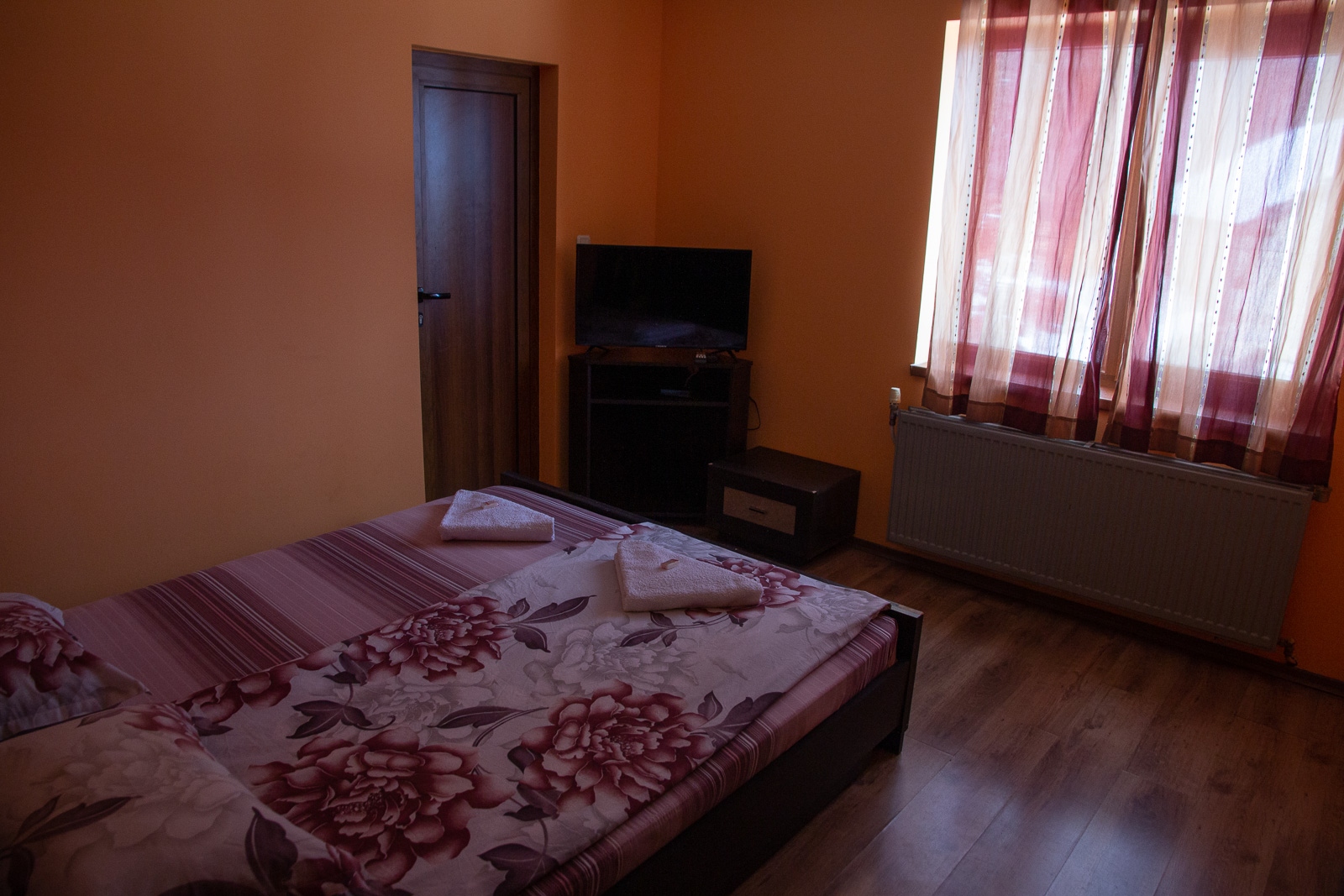 room interior with a bed, door, tv, and window