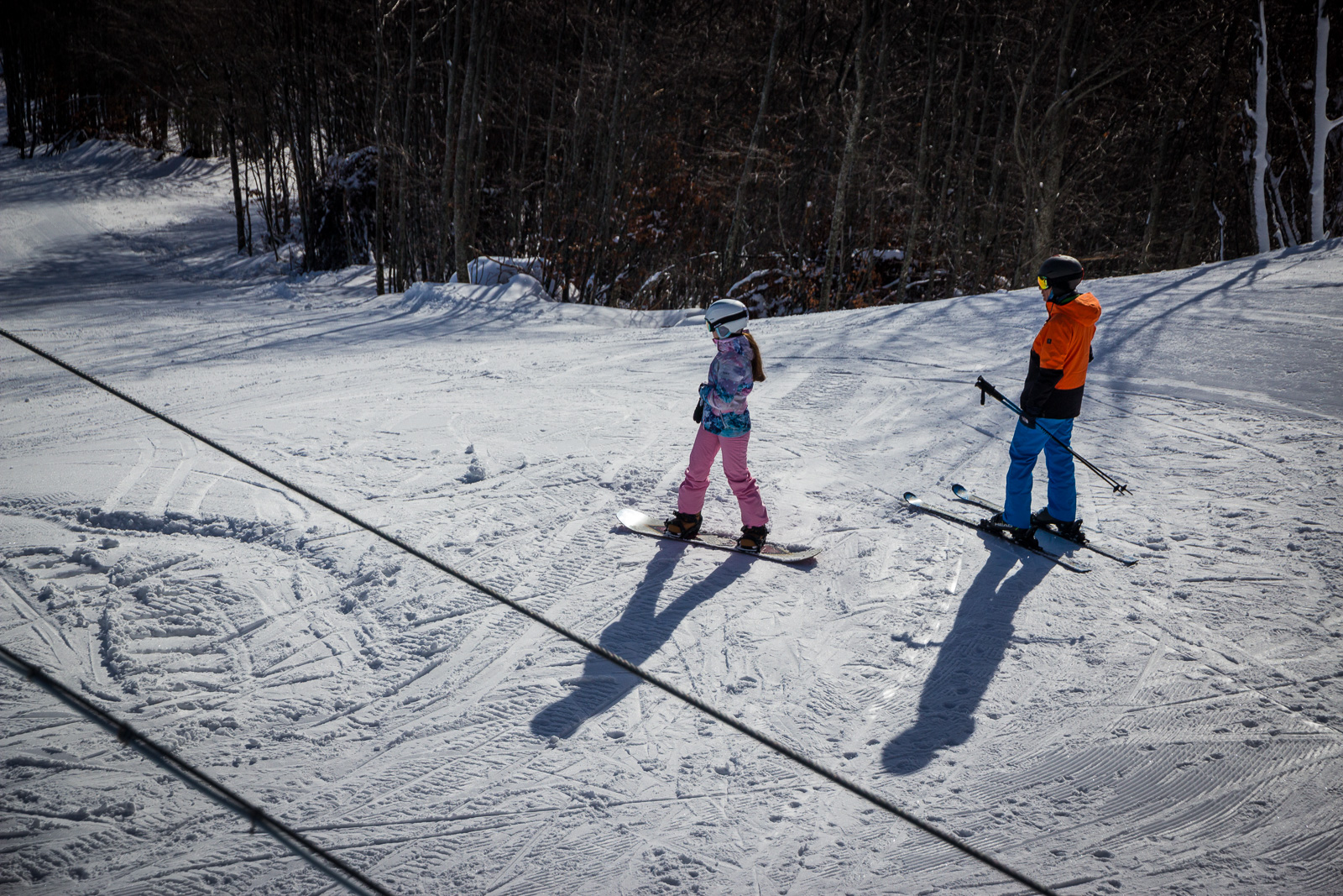 Young girl snowboarder and a boy skier on the slope