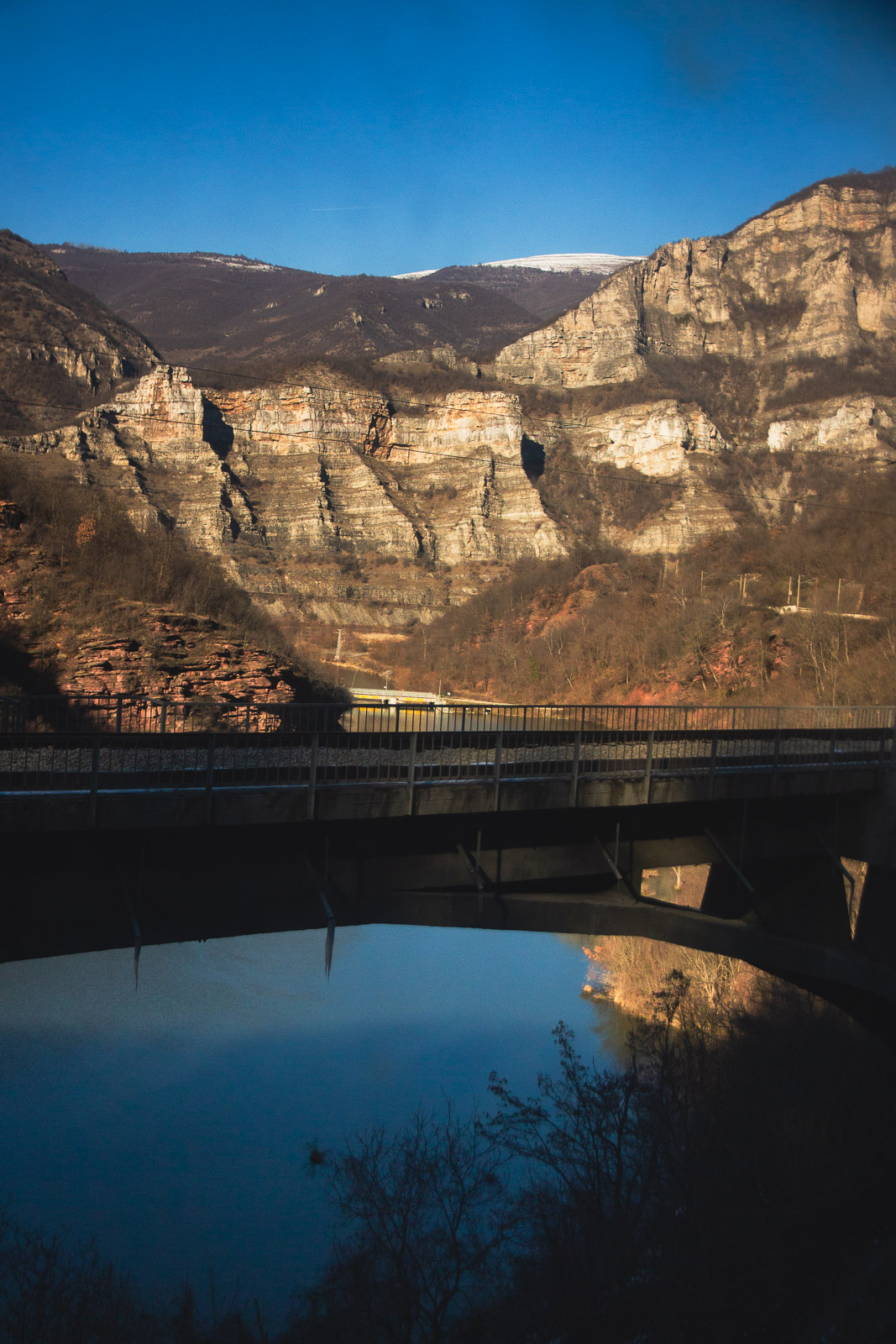 View towards a dam and cliffs from a train