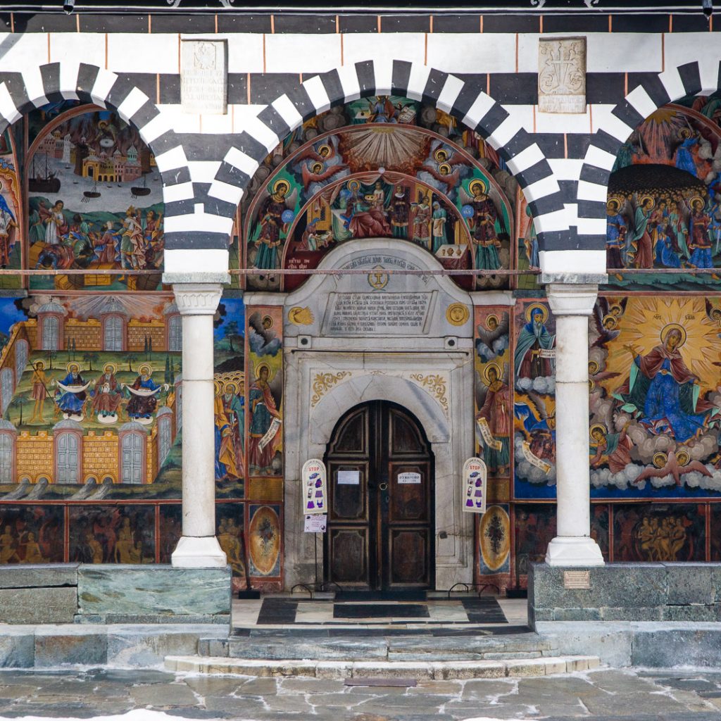 Colorful frescoes adorn church entrance.