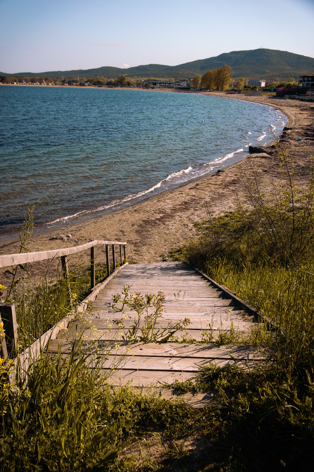 Wooden steps lead down to a sandy beach with gentle waves