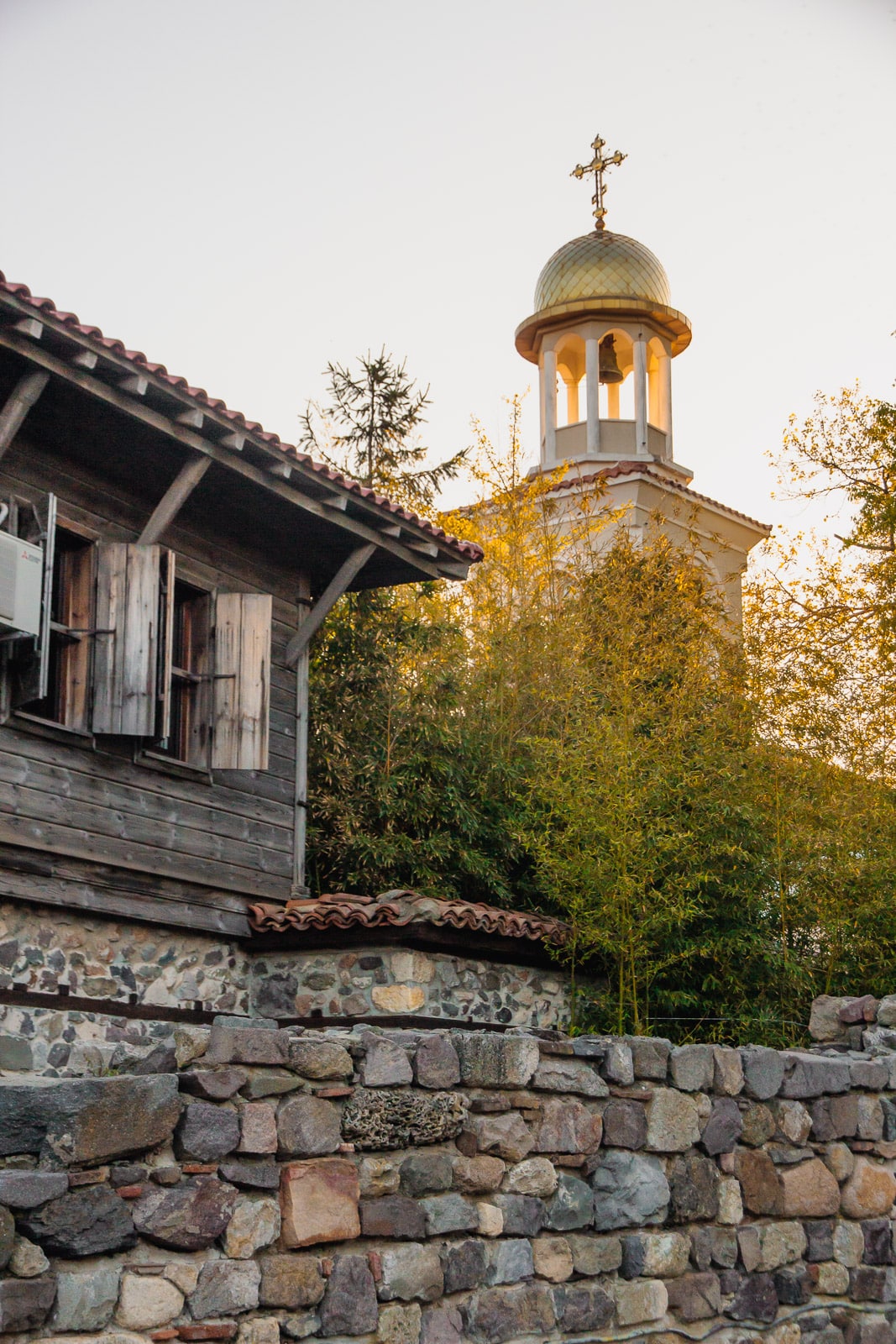 Sozopol old house with a church and a bell tower behind during a warm sunset