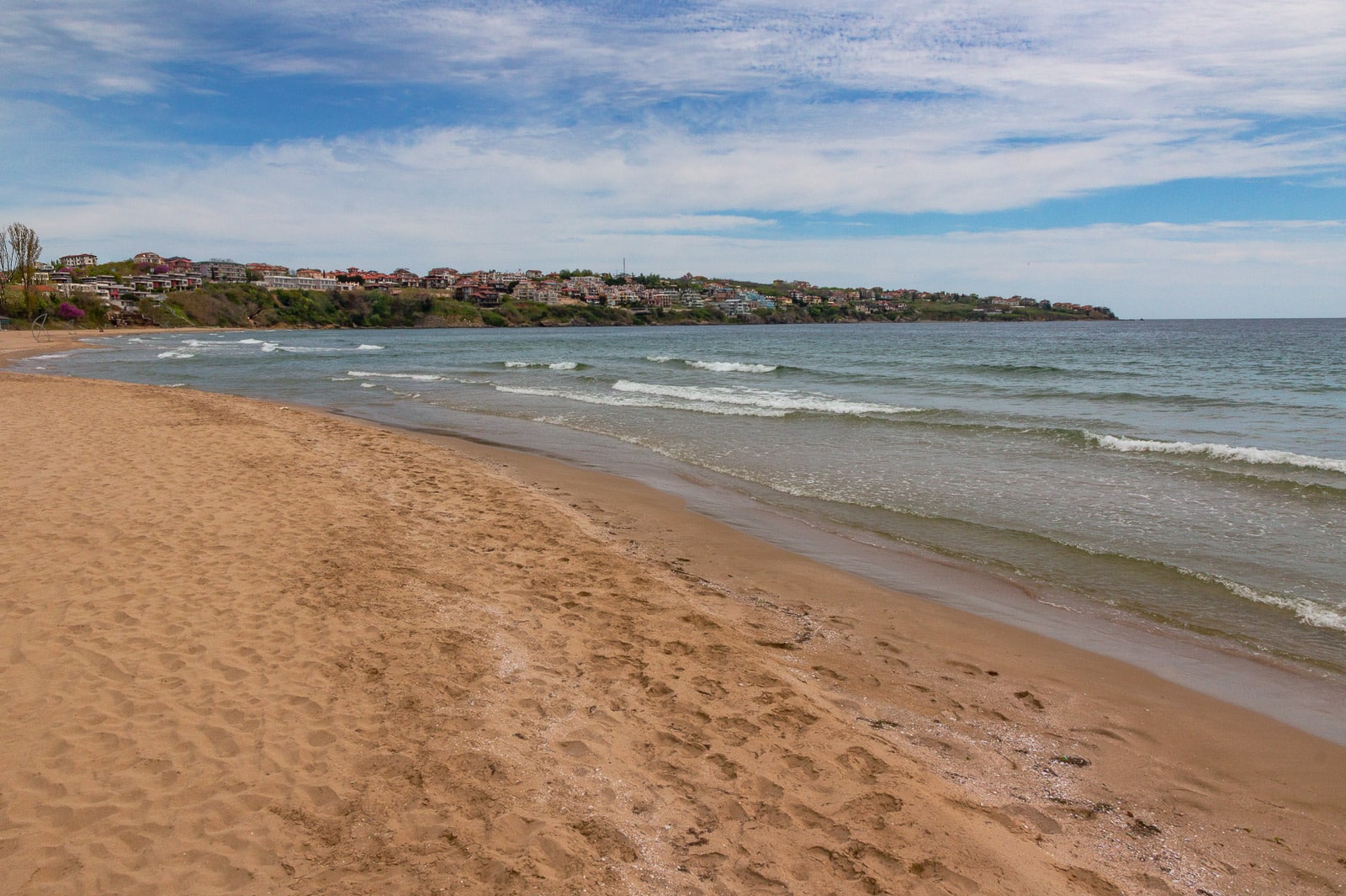 Sandy beach with gentle waves under a partly cloudy sky