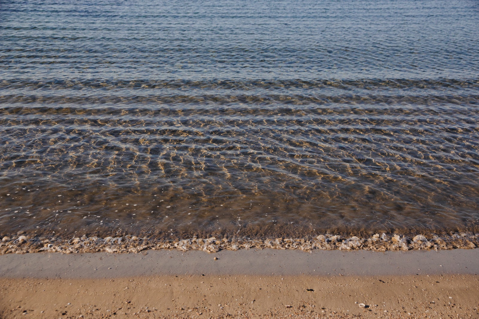 Calm waves gently lap against a sandy beach, creating a serene and peaceful scene