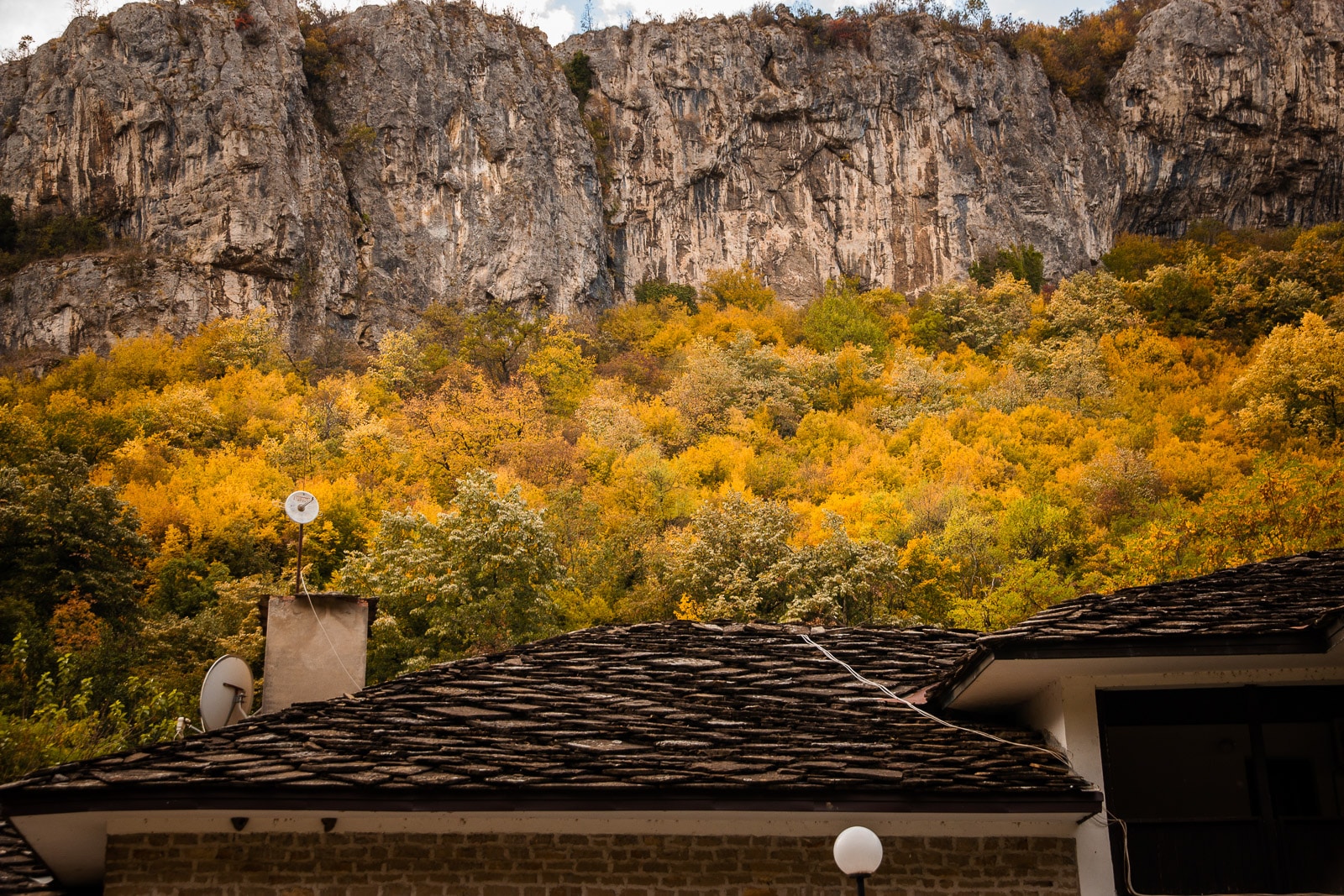 traditional Bulgarian roof with an autumn forest and cliffs behind it